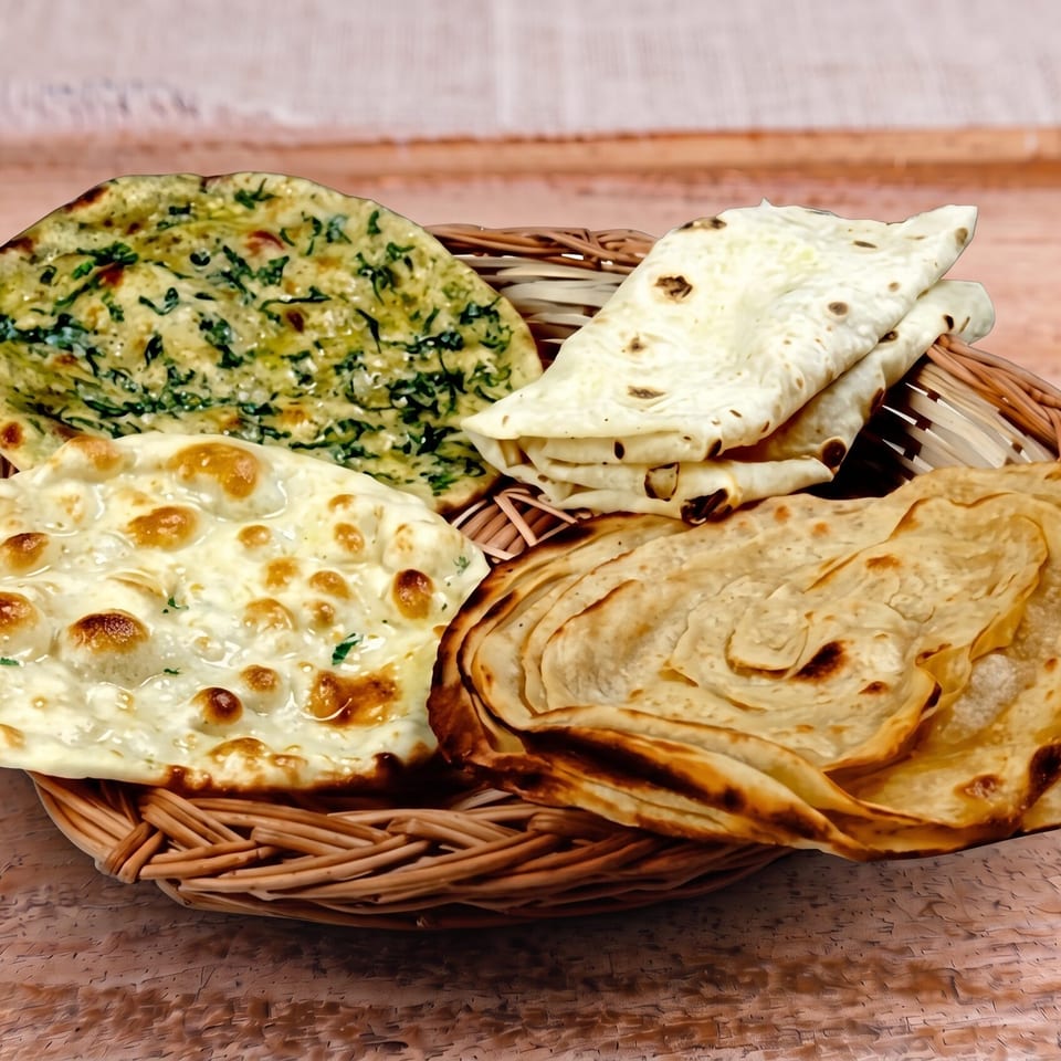 Woven basket filled with assorted Indian flatbreads, including naan, paratha, and roti.